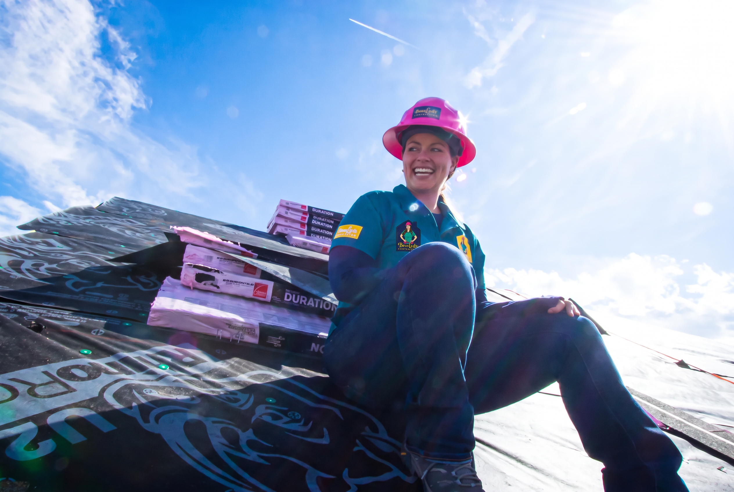 Alex Crawfurd seated on a Colorado residential roof, wearing a BossLady Contracting shirt logo